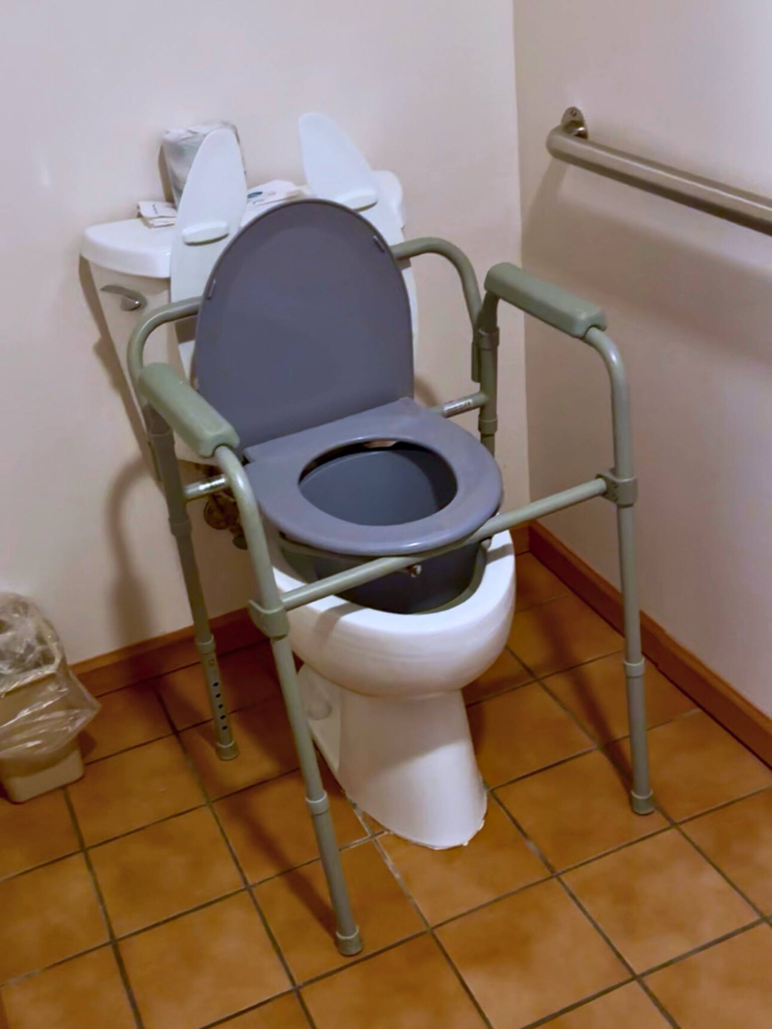 travel commode shown setup over a toilet to add height for accessibility