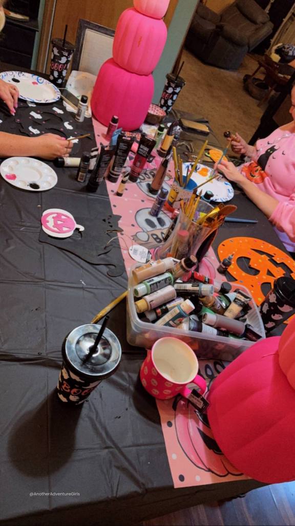 women gathered around a table painting wooden Halloween figures