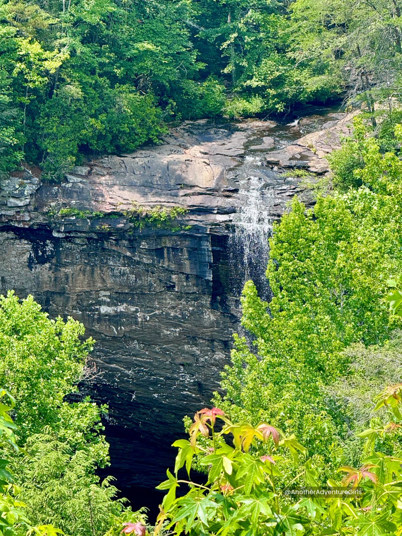 view of the waterfall through the trees from a lookout point higher up