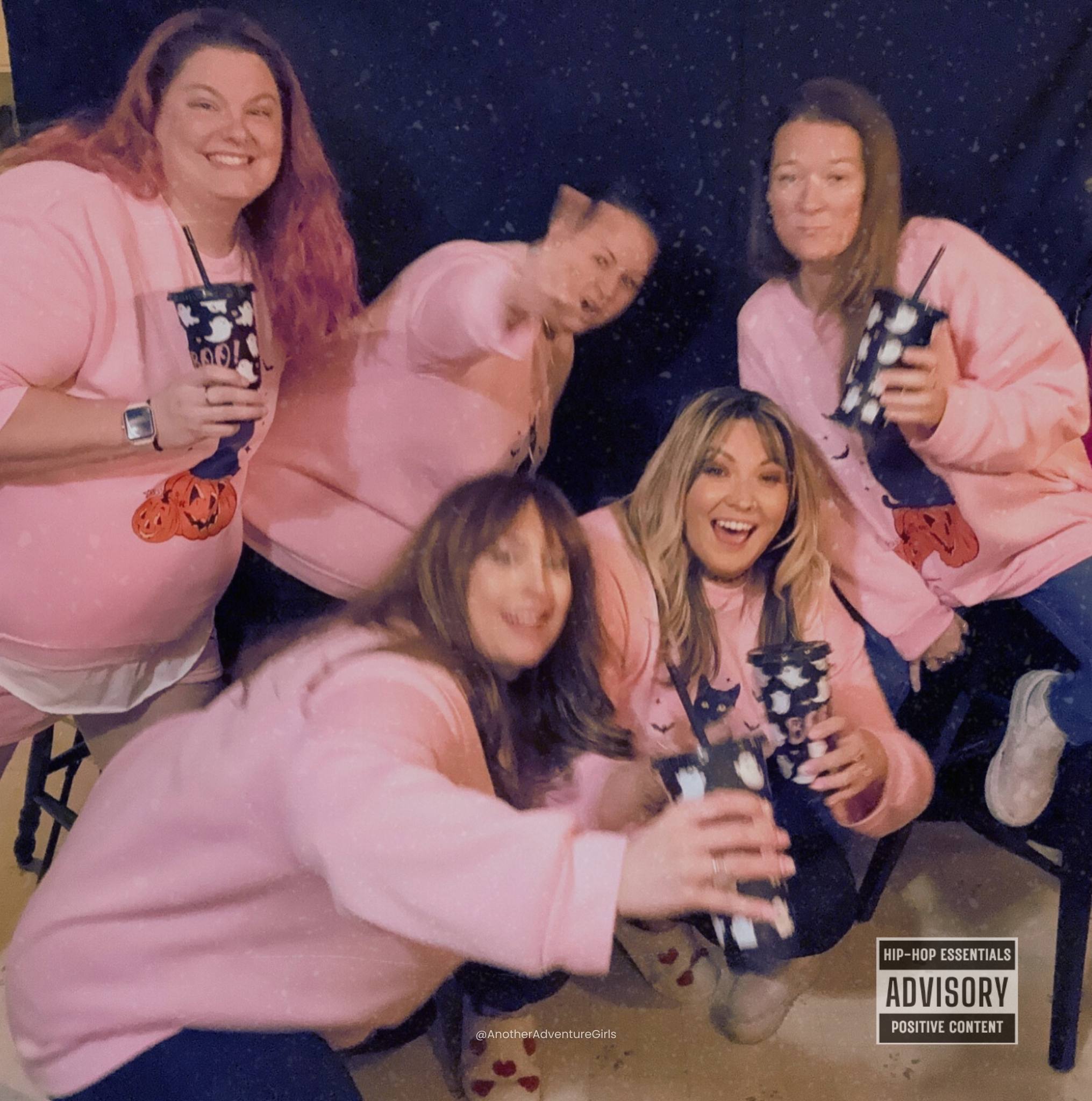 silly photo of five women wearing matching pink sweatshirts and falling