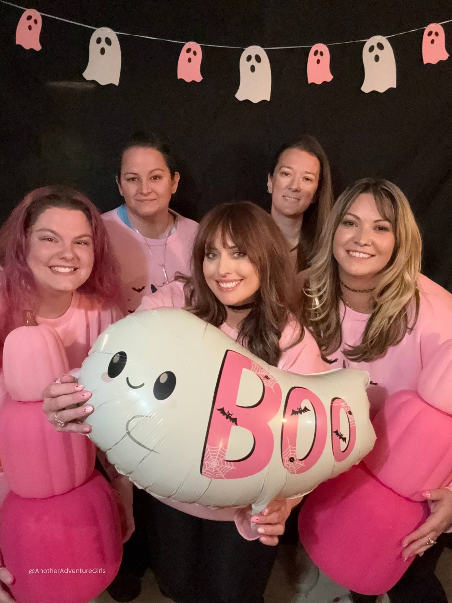 five women wearing matching pink sweatshirts smiling 