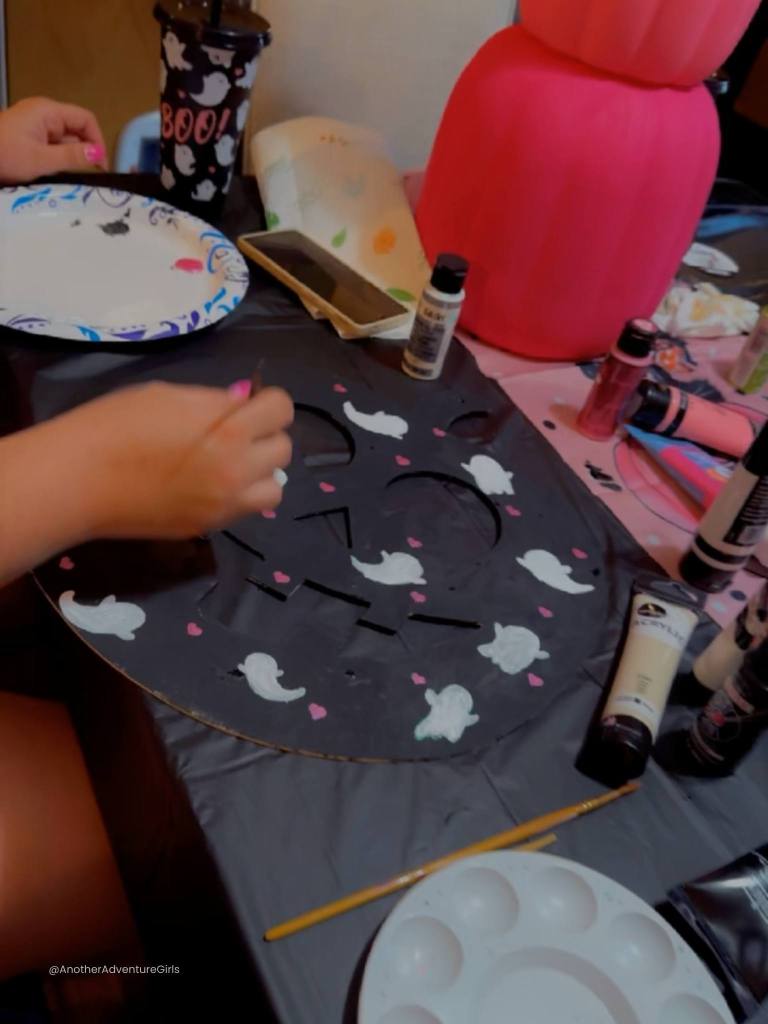 wooden figure of a jack o lantern painted black with white ghosts and pink hearts 