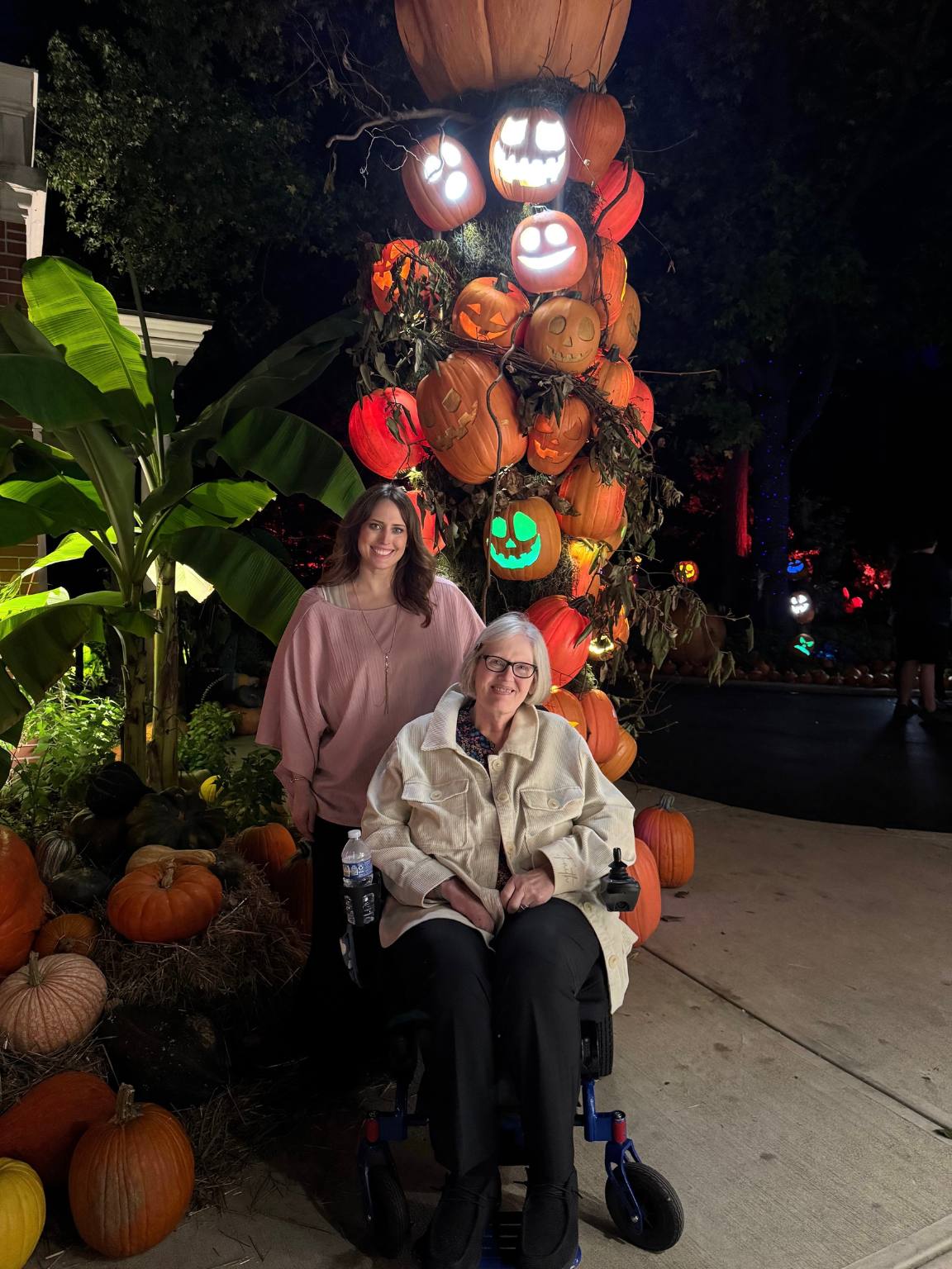 erin and her mom in front of a stack of pumpkins smiling
