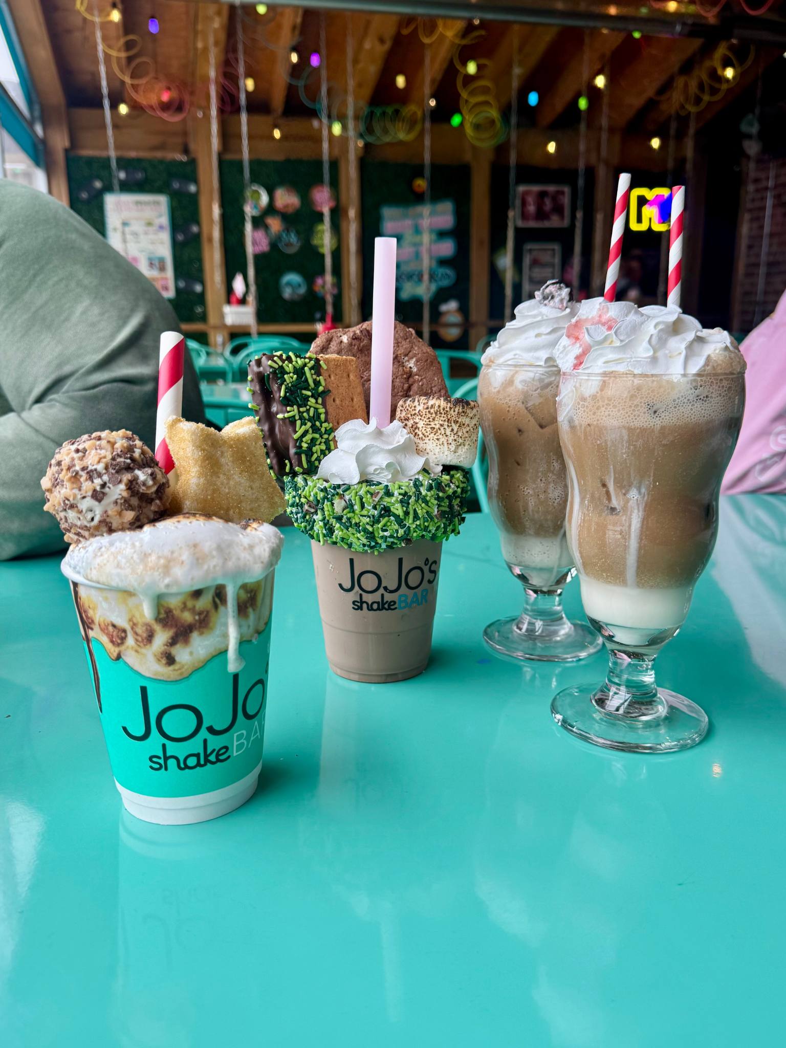 four drinks topped with whipped cream and sweets