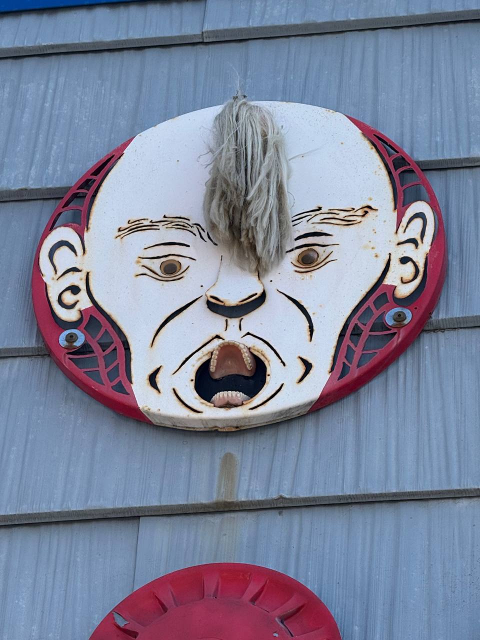 circual painted art piece with a face and dentures